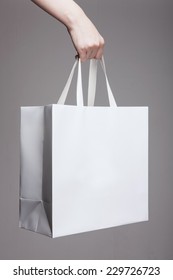 A Female(woman) Hand Hold A White Shopping Bag(paper Bag) And White Strings At The Studio.