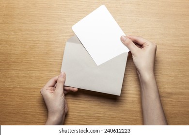 A Female(woman) Hand Hold(open) A Envelope And Post Card On The Wood Desk, Top View At The Studio. 