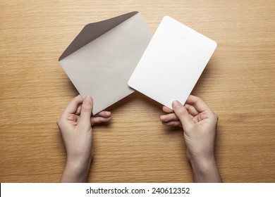 A Female(woman) Hand Hold(open) A Envelope And Post Card On The Wood Desk, Top View At The Studio. 