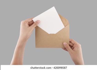 A female(woman) hand hold(open) a envelope and post card on the wood desk, top view at the studio.