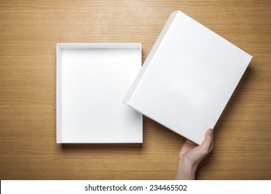 A Female(woman) Hands Hold A Empty(blank) White Box On The Desk(table) Top View At The Studio.