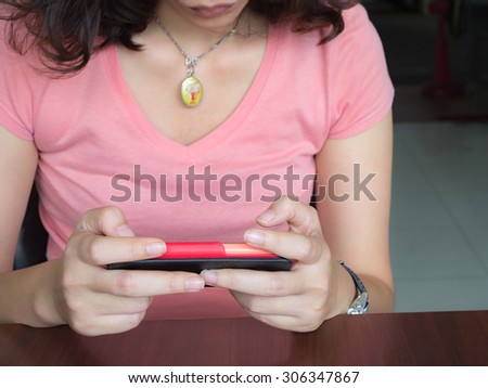 A female(woman) looking at her Smart Phone.