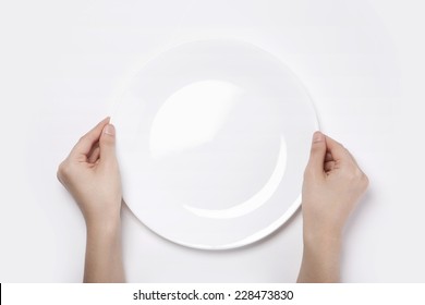 Female(woman) two hands hold a white dish(plate) isolated white and top view.