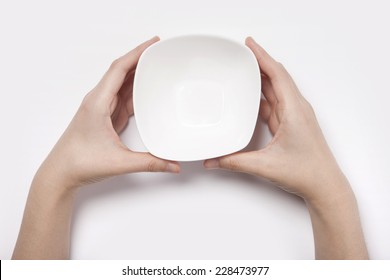 Female(woman) two hands hold a white bowl(plate) isolated white and top view.