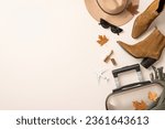 Feminine autumnal air journey vision. Top-view of mini plane, classy felt hat, cat-eye sunglasses, scarf, western boots, suitcase, maple leaves, lipstick on subtle pastel backdrop, room for text or ad