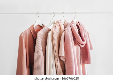 Feminine Clothes In Pastel Pink Color On Hanger On White Background. Spring Cleaning Home Wardrobe. Minimal Fashion Concept.