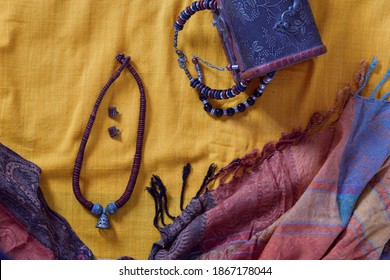 Feminine Clothing Saree And Shawl With Accessories Like Necklace And Ear Studs. Flat Lay On The Yellow Saree Background With Jewelry Box. Overhead View Of Casual Indian Style Outfit.