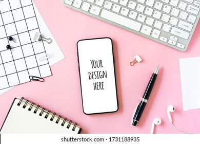 Feminine desk workspace with laptop, cell phone with blank screen, diary and white stationery on pink background. Flat lay mockup