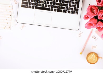 Feminine desktop close up, laptop computer keyboard, cup of coffee w/ latte art, pink flowers. Minimal cropped flat lay composition, notebook, cappuccino, tulips bouquet, white background. Copy space