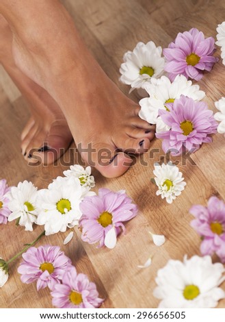 Feminine feet and flowers on a parquet floor.