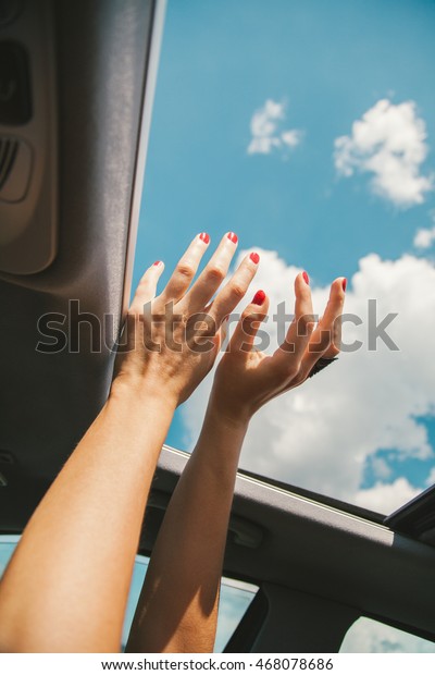 Feminine hands through the car window, blue
sky clouds on
background