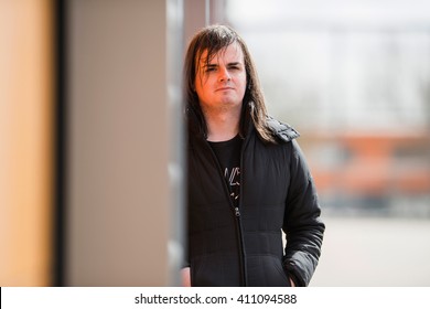 Feminine Man Leaning Against Industrial Metal Wall