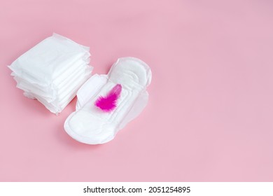 Feminine Sanitary Pads And Decorative Feather On Pink Background. Сoncept Of First Menstruation For Teenager. Copy Space