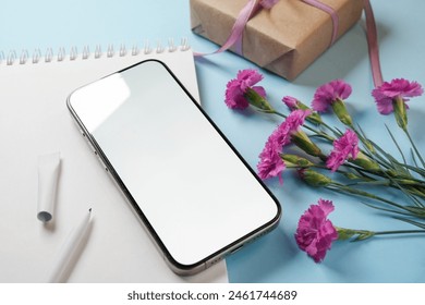 Feminine stationery composition. Smart phone, notebook with pen, gift and pink carnation flowers. Side view.  Mockup.  - Powered by Shutterstock