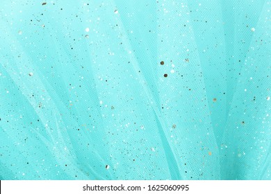 Feminine turquoise fabric tutu tulle skirt close up texture background with golden glitter