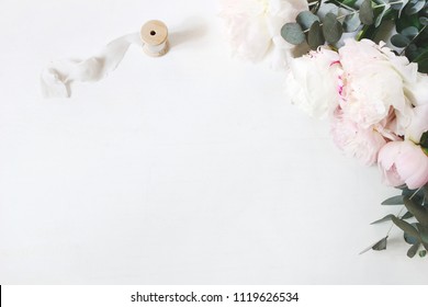 Feminine Wedding Or Birthday Table Composition With Floral Bouquet. White And Pink Peonies Flowers, Eucalyptus And Silk Ribbon. Festive Greeting Card, Invitation. Empty Space. Flat Lay, Top View.