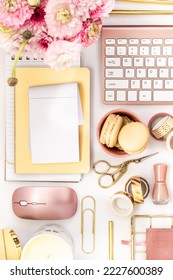 A femininely styled desktop in shades in gold and dusty pink with modem stationery. Lifestyle theme inspired by the office workspace of a stylish woman. Flat lay with fresh flowers pink keyboard and