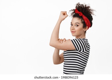 Feminsm and women rights. Strong brunete woman showing we can do this strong hand gesture, blex biceps muscles and smiling confident, standing against white background