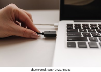 Femle hand inserting black USB flash drive into computer laptop