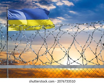 A fence with barbed wire against the background of a colorful sky and a flagpole with the flag of Ukraine protects the state's border from illegal migration. - Powered by Shutterstock