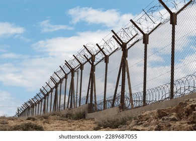 A fence with barbed wire. A long wire fence with barbed wire. Protection of borders and military territories.