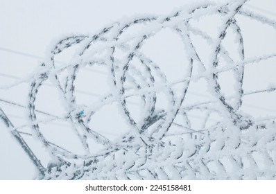 a fence with barbed wire on the border in winter, the thorn is covered with a snowdrift of white snow