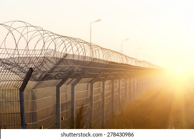 fence with barbed wire on the border of the object at dawn with fog in the summer, russia