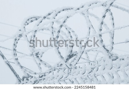 a fence with barbed wire on the border in winter, the thorn is covered with a snowdrift of white snow