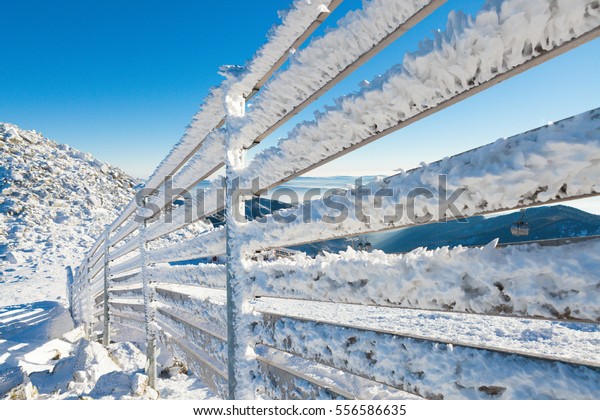 Fence covered by heavy snow on a sunny day after\
a heavy blizzard