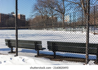 Fence And Empty Benches At A Snow Covered Park Next To Public Housing In Astoria Queens New York During The Winter