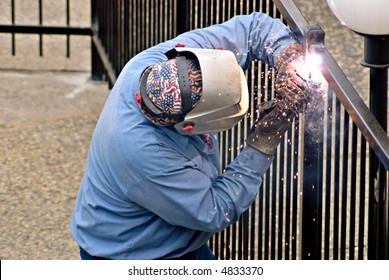 Fence Installation Worker Welds A Seal On A New Fence Post