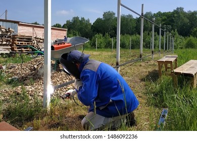 A Fence Installer Welds A Metal Profile To A New Fence Post.