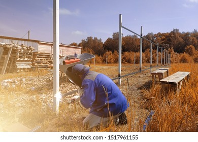 A Fence Installer Welds A Metal Profile To A New Fence Post.