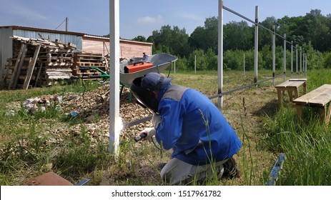 A Fence Installer Welds A Metal Profile To A New Fence Post.