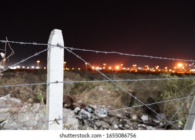 Fence Of The Jungle Showing Distant City Lights