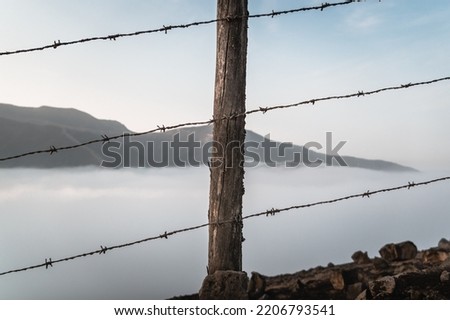 fence made with wood and metal spikes, with the mountains behind.
