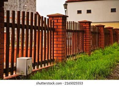 A Fence Made Of Wooden Rails, And With Posts Made Of Clinker Bricks .