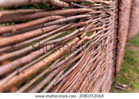 A fence made of woven branches to create an environmentally sustainable wall in the backyard garden. Background, texture, decor element