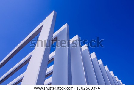 The fence on the sky background against the wall And abstract architecture contrasting with the blue sky With clear and beautiful light shadows Modern concepts