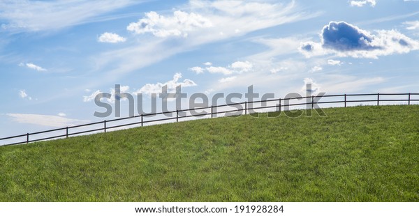 A fence running along a hill climb. As a way\
parts of the land from the\
sky.
