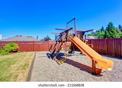 Fenced Backyard With Lawn And Playground For Kids.