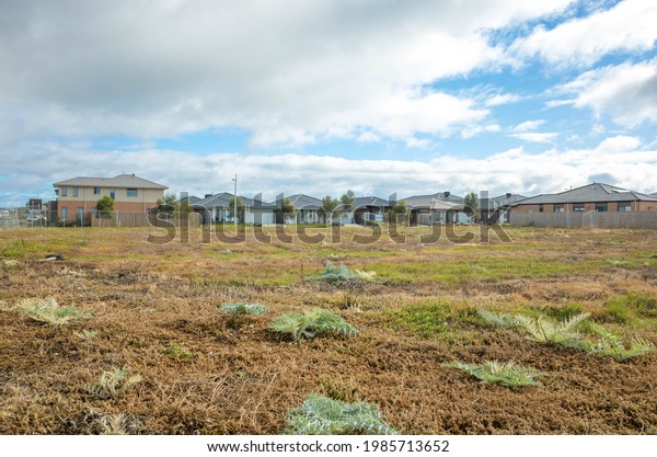 Fenced\
vacant land near some Australian new residential suburban houses.\
Concept of real estate development, housing, land for sale and a\
new suburb, Tarneit, Melbourne, VIC\
Australia.