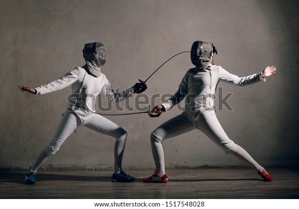 Fencer\
woman with fencing sword. Fencers duel\
concept.