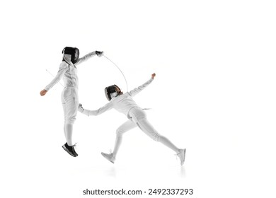 Fencers' blades clash as they spar, perfecting their movements for upcoming match against white studio background. Concept of professional sport, competition, strength and power, action. Ad - Powered by Shutterstock