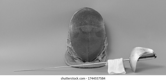 Fencing Helmet And Fencing Rapier Isolated On Gray Background