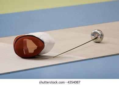 A fencing mask and a fencing sword on the floor