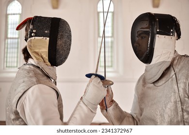 Fencing, sword and people start fight in sports training, exercise or challenge in hall. Martial arts, combat and athlete fencers with mask and costume for fitness, competition or target in swordplay - Powered by Shutterstock