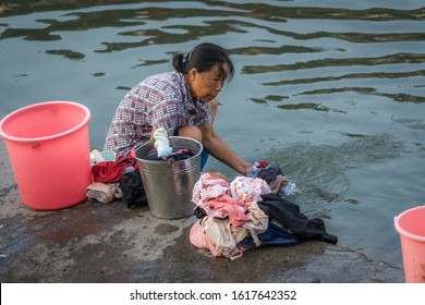 Feng Huang, China -  August 2019 : Old Woman Doing Laundry On The Riverbank Of Tuo River,  Feng Huang Old Town