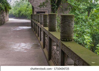 Fengdu, China - May 8, 2010: Ghost City, Historic Sanctuary. Brown Stone With Green Mold Bridge Of Helplessness In Rain And With Green Foliage Around. Artfull Frescoes.