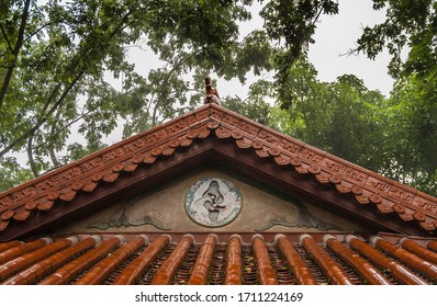 Fengdu, China - May 8, 2010: Ghost City, Historic Sanctuary. Closeup Of Red Chinese Architectural Roof Structure Under Green Foliage. 2 Birds Fresco N Triangle.